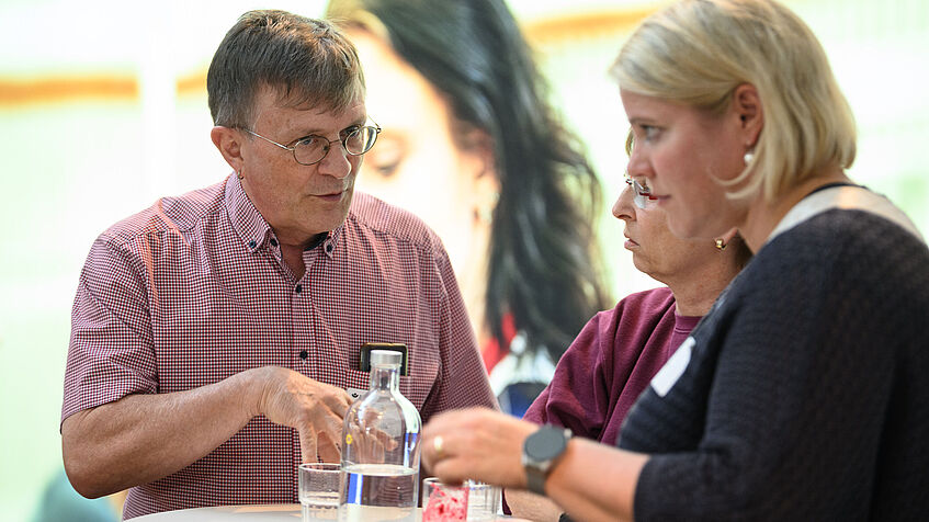 Ein Mann und eine Frau stehen an einem Tisch und unterhalten sich angeregt. 