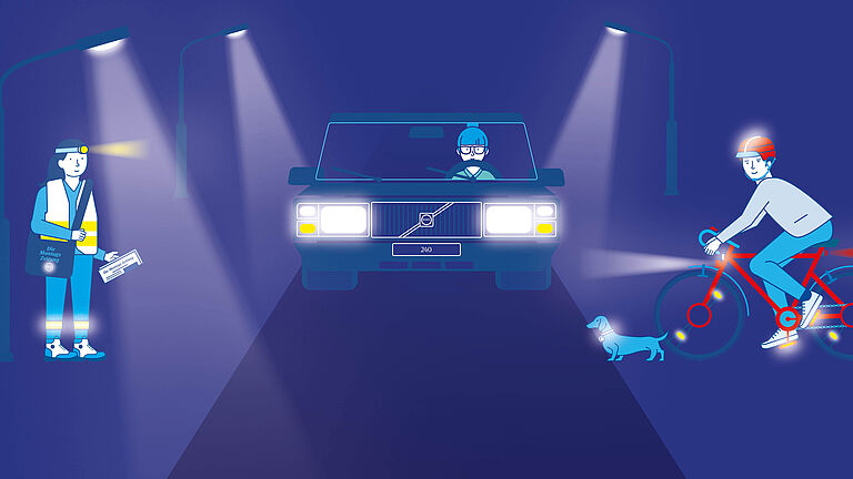 Im Scheinwerferlicht eines Autos: Eine Zeitungszustellerin, mit Warnweste, Refektoren und Stirnlampe sowie ein Fahradfahrer mit heller Kleidung und reflektierendem Helm. Am Fahrrad Licht und Refelektoren. Daneben eiin Hund, der ein reflektierendes Halsband trägt.