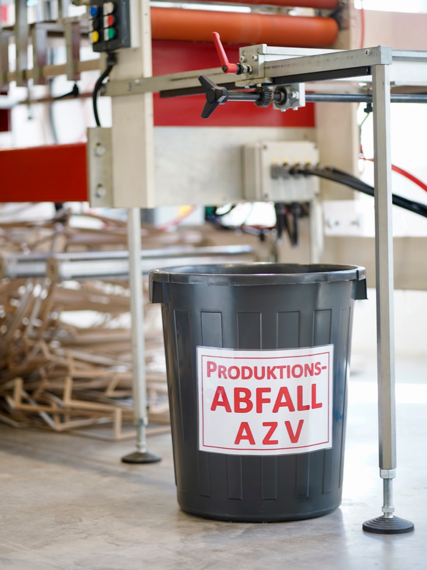 Beschrifteter Abfalleimer an einer Produktionsmaschine